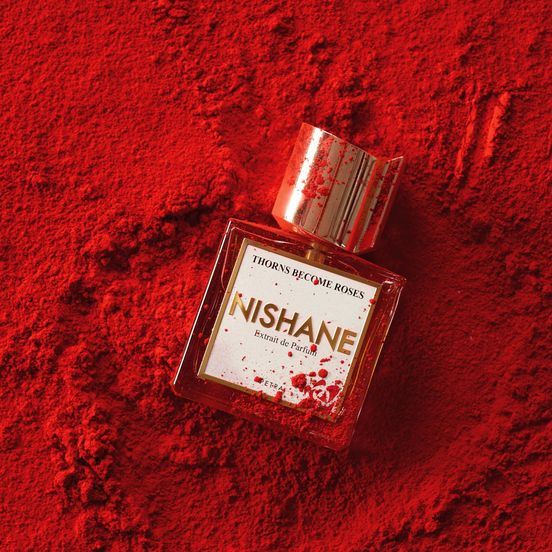 Nishane Thorns Become Roses fragrance bottle in red powder